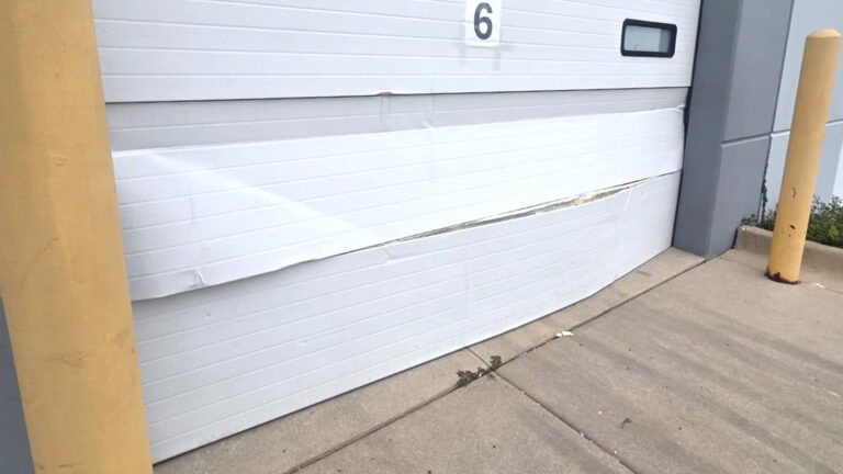 Two garage door sections bent by a car in Wheeling, Illinois; assessed by Firstline Garage Door Repair.